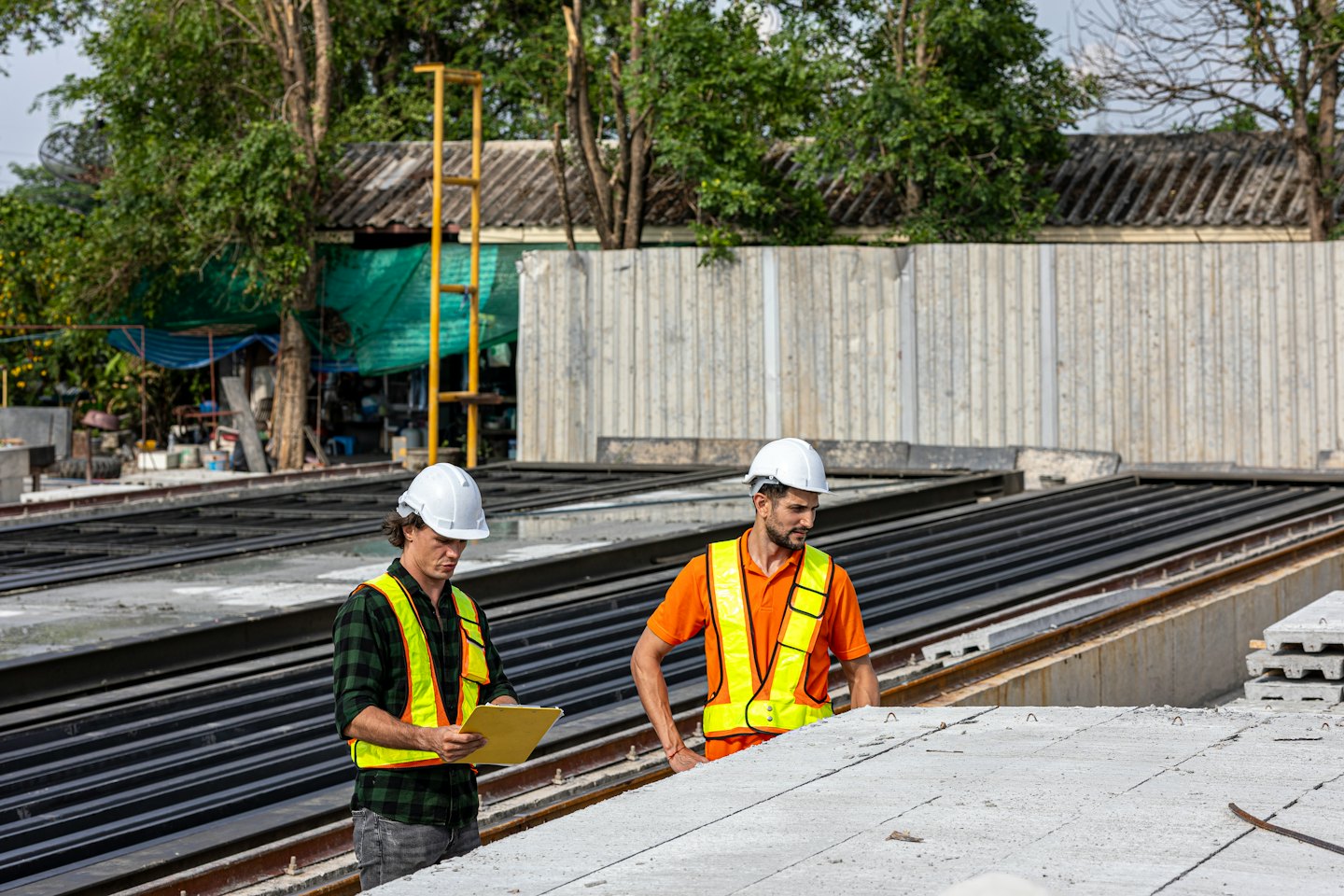 Bauarbeiter in Schutzhelmen inspizieren Betonbauteile im Freien.
